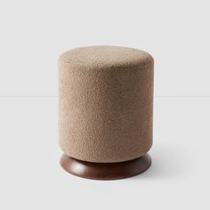 a round stool with a wooden base on a white background, it is made from wool