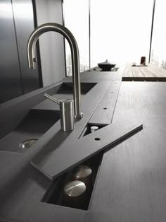 a kitchen sink with two faucets in the center and an open drain on the side