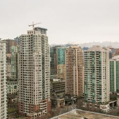 an aerial view of some very tall buildings in the city with mountains in the background