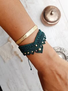 a woman's arm wearing a green bracelet with gold accents and beads on it