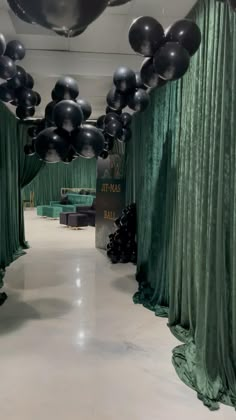 black and silver balloons are hanging from the ceiling in an elegant room with green drapes