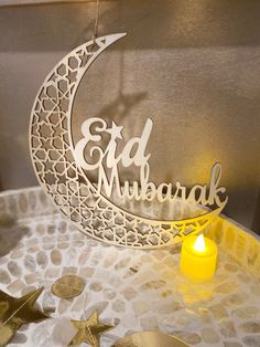 a candle is lit next to a metal sign that says eid mubarak