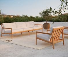 an outdoor seating area with white cushions and wooden furniture