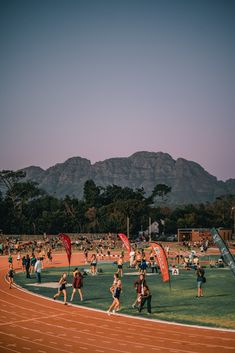 a group of people running on a track with mountains in the backgrouds