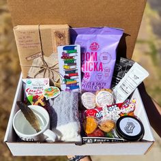 a person holding a box filled with food and snacks