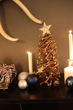 a wooden christmas tree sitting on top of a table next to candles and other decorations