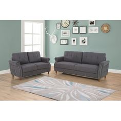 two gray couches sitting on top of a wooden floor next to a blue wall