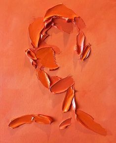 an orange background with some brown paint on the ground and one piece of paper in the shape of a man's face