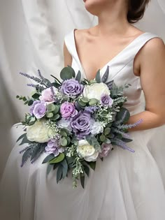 a woman in a white dress holding a bouquet of purple and white flowers on her wedding day