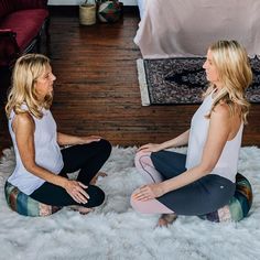 two women sitting on the floor talking to each other