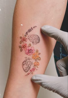 a woman's arm with flowers and hearts tattooed on the left side of her leg