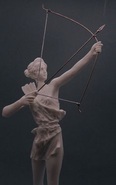 a statue of a woman holding a bow and arrow in her hands with one hand