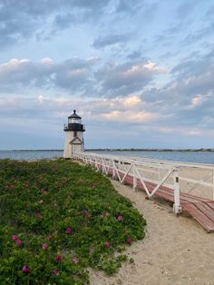 a light house sitting on top of a sandy beach next to the ocean under a cloudy sky