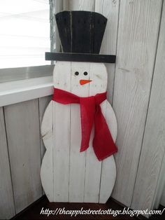 a wooden snowman with a black hat and red scarf on it's head