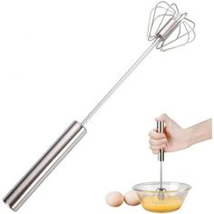 a hand holding a metal mixer attachment over a bowl filled with eggs and an egg beater