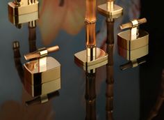 four gold candlesticks are placed on a glass surface