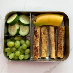 a metal container filled with different types of food next to cucumbers and bananas