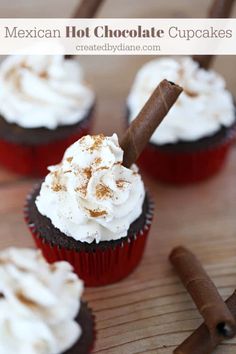 several cupcakes with white frosting and cinnamon stick on top, sitting on a wooden table