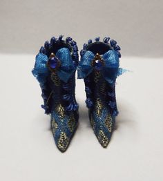 two pairs of blue shoes with bows and beads on the toes are sitting on a white surface