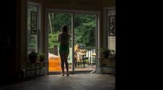 a woman standing in front of a sliding glass door with her back to the camera