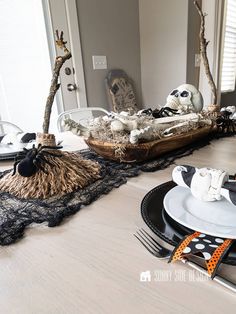 the table is set for halloween with black and white decorations