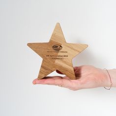 a wooden star shaped award being held by a person's hand on a white background