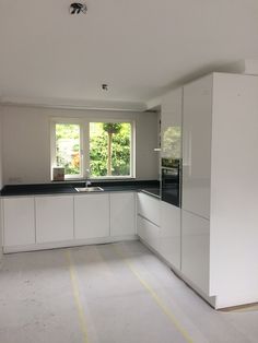 an empty kitchen with white cabinets and black counter tops in the process of remodeling