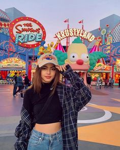 a woman standing in front of an amusement park with a clown mask on her head