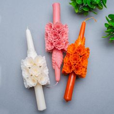 three different colored candles with flowers on them