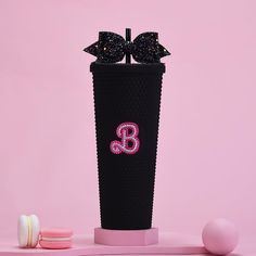 a pink and black cup with two bows on it