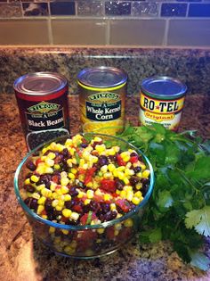 corn and black beans in a glass bowl next to three cans of rotini sauce