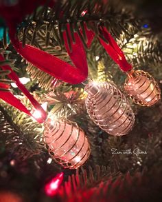 christmas ornaments hanging from the branches of a tree with red ribbons and lights on them