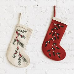 two christmas stockings hanging on the wall next to each other, one decorated with red and green leaves