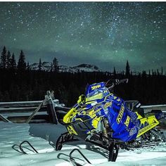 a blue and yellow snowmobile parked in the snow