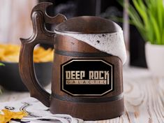 a wooden beer mug sitting on top of a table next to a potted plant