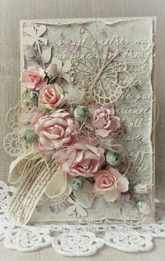 a close up of a card with flowers and lace on the edge, along with white doily