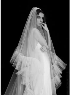 a black and white photo of a woman in a wedding dress with a veil on her head