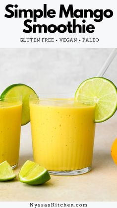 two glasses filled with orange smoothie next to limes and an orange on the side