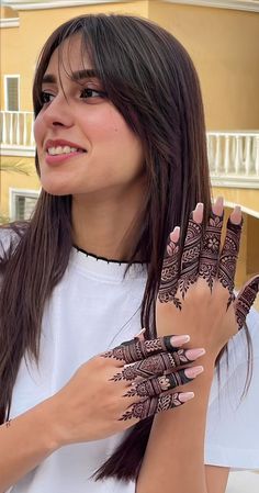 a woman with henna tattoos on her hands and hand is smiling at the camera