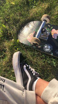 someone is sitting on the grass with their skateboard