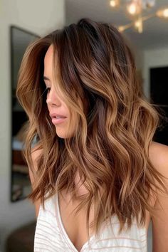 Woman with wavy brown hair with blonde highlights looking to the side. Dark Skinned Hair Color Ideas, Cinnamon Highlights On Light Brown Hair, Brown Hair With Red And Caramel Highlights, Cinnamon Swirl Hair Color, Brunette Babylights Sun Kissed, Cinnamon Balayage Brunettes, Balayage For Red Heads, Brunette Balayage Hair Red Undertones, Cinnamon Bayalage Brunette