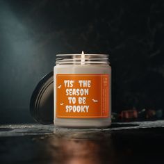 an orange and white candle with the words tis the season to be spooky on it