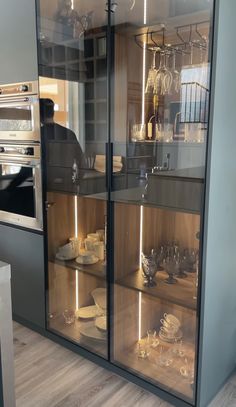 a kitchen with glass shelves filled with dishes and utensils on top of them