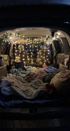 the back of a car with lights in it's trunk and blankets on the bed