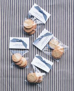 four cookies wrapped in clear cellophane are sitting on a striped tablecloth with tags