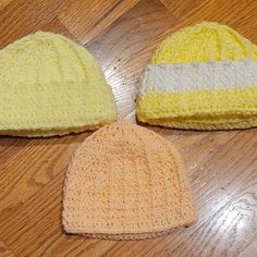 three crocheted hats sitting on top of a wooden floor