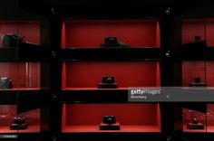 red shelves filled with cameras and other items in a dark room at the camera museum