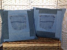 two blue jeans pillows sitting on top of a wicker basket next to each other