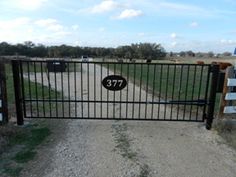 a gate that has the number 377 on it and is next to a dirt road