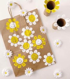 a brown paper bag with yellow and white flowers on it next to some coffee cups